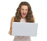 Angry young woman yelling on laptop