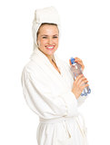 Happy young woman in bathrobe with water bottle