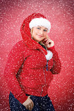 Joyful pretty woman in red santa claus hat smiling with snowflakes