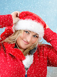 Joyful pretty woman in red santa claus hat smiling with snowflakes
