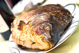 Baked carp in a plate with wine in background