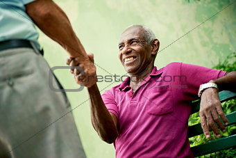 old black and caucasian men meeting and shaking hands in park