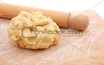 Wooden rolling pin and a fresh ball of pastry on a floured board