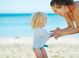 Happy mother and baby girl playing on beach