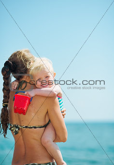 Baby girl hugging mother on beach