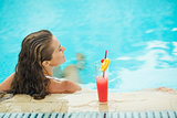 Young woman at pool with cocktail. rear view