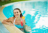 Portrait of smiling young woman at pool with cocktail