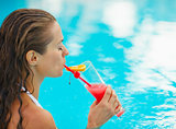 Young woman at pool drinking cocktail