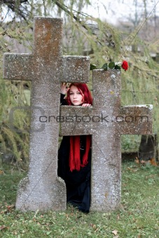 Gothic girl with a rose on a cemetery