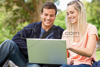 Young people sitting while using a laptop
