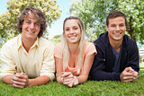 Portrait of three smiling students in a park