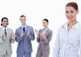 Close-up of a woman smiling with business people applauding whil