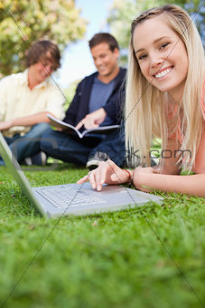 Close-up of a girl using a laptop while lying in a park