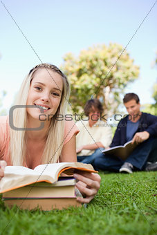 Portrait of a girl lying while reading books in a park
