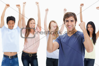 Man clenching his fists with people behind him raising their arm