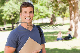 Portrait of a student smiling while holding a textbook