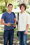 Portrait of two smiling male students with a touch pad