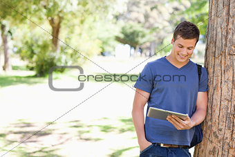 Student leaning against a tree