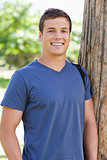 Close-up of a young man leaning against a tree