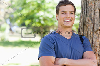 Portrait of a young man leaning against a tree