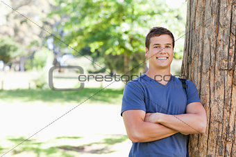 Portrait of a muscled student leaning against a tree