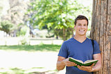 Portrait of a smiling toothy student holding a textbook