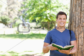 Portrait of a smiling toothy student holding a textbook