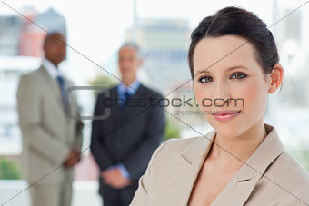 Young secretary standing in front of two executives in a relaxed
