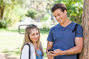 Close-up of a student showing his smartphone screen to a girl