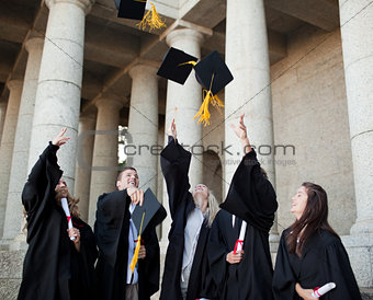 Smiling graduates throwing their hats in the sky