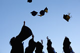 Five graduates throwing their hats in the sky 