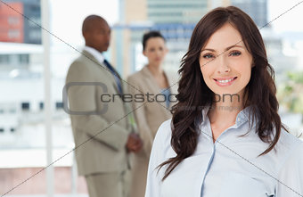 Young smiling businesswoman standing in front of her colleagues