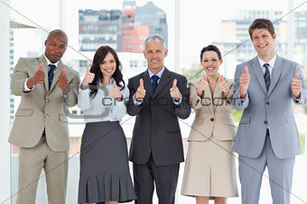 Business team showing success by putting their thumbs up