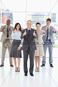 Business team standing together with their thumbs up in success