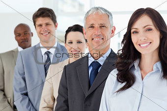 Four smiling employees standing upright around their director