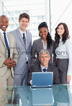 Mature businessman sitting at the desk behind a laptop and surro