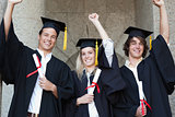 Graduates holding their diploma while raising arm