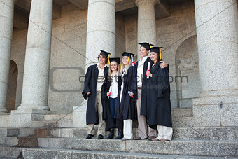 Five graduates posing while holding their diploma