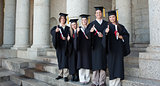Five happy graduates posing the thumb-up