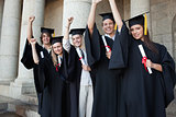 Five happy graduates posing the arm raised
