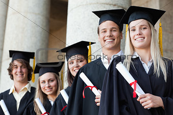 Close-up of five smiling graduates posing