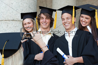 Close-up of a graduate taking a picture of her smiling friend