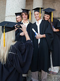 Blonde graduate taking a picture of her friend