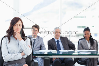 Confident businesswoman sitting with her hand on her chin while 
