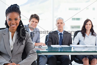 Serious businesswoman sitting in front of her team while smiling