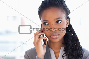 Young earnest employee talking on the phone in front of a bright