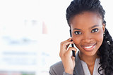 Young smiling businesswoman looking ahead while talking on a pho