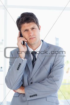 Serious businessman making a call while looking at the camera