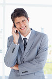 Smiling businessman crossing his arms while making a call
