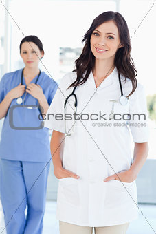 A nurse standing upright while her colleague is standing behind 